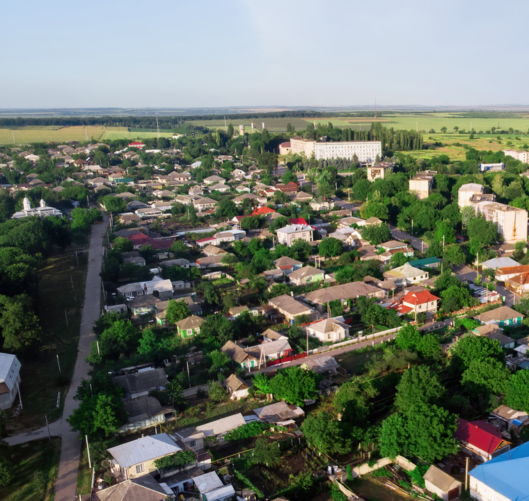 Donduseni with multiple residential buildings and greenery, fields on the background, view from the drone in Moldova